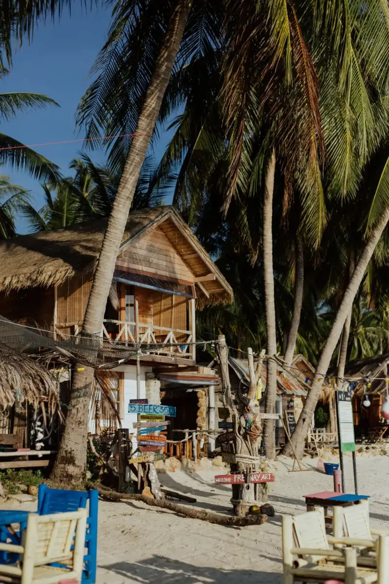Wooden beach cabanas under palm trees on white sand