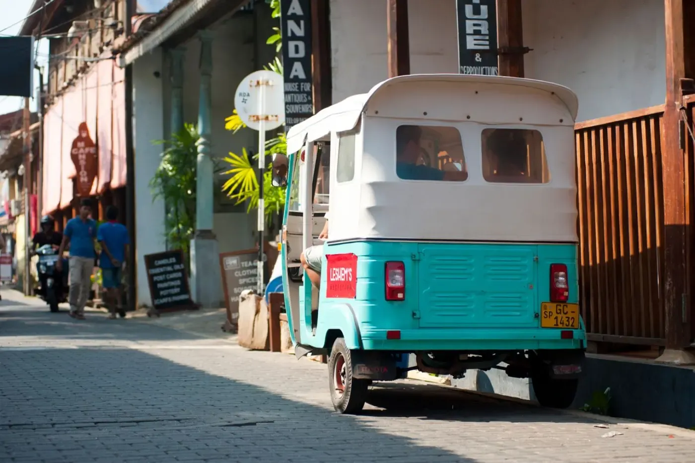 A tuk-tuk parked on a quiet old town street lined with shops